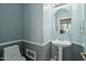 Charming powder room featuring pedestal sink, oval mirror, and elegant wainscoting at 16753 W Bristol Ln, Surprise, AZ 85374