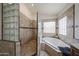 Elegant bathroom with a glass block shower and separate soaking tub with neutral tile at 17806 N 54Th Ln, Glendale, AZ 85308