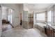 Spacious bathroom boasts a walk-in glass block shower, soaking tub, and vanity with granite countertops at 17806 N 54Th Ln, Glendale, AZ 85308