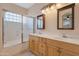 Well-lit bathroom featuring double sinks, wood cabinets, a glass block window and shower-tub combination at 17939 N Encanto Dr, Surprise, AZ 85374