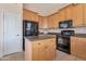 Well-lit kitchen features wooden cabinetry and black appliances at 17939 N Encanto Dr, Surprise, AZ 85374