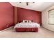A primary bedroom with a red accent wall, ceiling fan, and neutral carpeting at 30 S 230Th Ave, Buckeye, AZ 85326