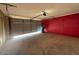 Spacious garage featuring a roll-up door, concrete floor, and red accent wall, offering ample storage and parking at 3150 E Corrine Dr, Phoenix, AZ 85032