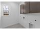 Functional laundry room with upper cabinets, window and hook ups for washer and dryer at 32497 N 135Th Dr, Peoria, AZ 85383