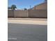 View of the sidewalk, street, brick wall, and wooden fence with palm trees in the distance at 5139 E Tano St, Phoenix, AZ 85044