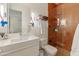 Well lit bathroom featuring a glass enclosed shower with unique orange tiling and a modern white vanity at 523 W Vista Ave, Phoenix, AZ 85021