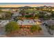 An aerial view of a lit property with a sparkling pool and beautiful mountain views at sunset at 5837 E Presidio Rd, Scottsdale, AZ 85254