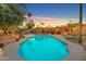 Backyard pool area featuring a sparkling pool, covered patio, string lights, lush greenery, and mature trees at 5837 E Presidio Rd, Scottsdale, AZ 85254
