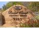 Stone sign for Desert Camp Community Center, features the address with desert landscaping and blooming flowers at 9270 E Thompson Peak Pkwy # 367, Scottsdale, AZ 85255