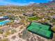 An aerial view showcases the community tennis courts nestled within a desert landscape and lush greenery at 9270 E Thompson Peak Pkwy # 367, Scottsdale, AZ 85255