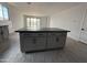 Kitchen island with dark countertops and gray cabinets, centered in a spacious open-concept kitchen and living area at 9539 W Parkway Dr, Tolleson, AZ 85353