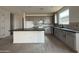 View of kitchen with gray cabinets, dark countertops, an island, and wood-look tile flooring at 9539 W Parkway Dr, Tolleson, AZ 85353