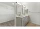 Bright bathroom featuring double sinks with modern fixtures and a walk-in closet with shelving at 9740 E Baltimore Cir, Mesa, AZ 85207