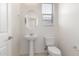 Stylish powder room featuring a pedestal sink, oval mirror, and modern fixtures, illuminated by natural light at 1176 N 169Th Ave, Goodyear, AZ 85338