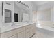 Bright bathroom showcasing a double sink vanity with a large mirror, soaking tub, and decorative tiled floor at 2821 E Pontiac Dr, Phoenix, AZ 85050