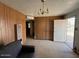 A simple living room featuring wood paneling, outdated furniture, and an exterior door at 3155 E Mobile Ln, Phoenix, AZ 85040