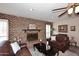 Inviting living room featuring a brick fireplace, wood mantle, and comfortable leather sofas at 7537 W Bluefield Ave, Glendale, AZ 85308