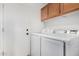 Functional laundry room equipped with modern washer and dryer units, complemented by overhead cabinetry for storage at 960 W Hudson Way, Gilbert, AZ 85233