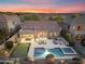 Aerial view of backyard with pool, putting green, outdoor kitchen and lounge area, all under a colorful sunset at 10478 E Sheena Dr, Scottsdale, AZ 85255