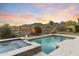 A beautiful backyard with a pool, spa, and putting green is set against a scenic mountain backdrop at 10478 E Sheena Dr, Scottsdale, AZ 85255