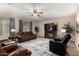 Spacious living room with ceiling fan, cozy seating arrangement, large windows, and fireplace at 12300 N 142Nd Ln, Surprise, AZ 85379