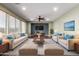 The staged living room features a ceiling fan, recessed lighting, wood flooring and modern furniture at 12473 W Montgomery Rd, Peoria, AZ 85383