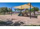 Community playground area with swings, slide, and shade structure on sand at 13337 W Evans Dr, Surprise, AZ 85379