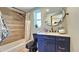 Bathroom with elegant blue vanity, marble countertop, oval mirror, and tiled shower with modern fixtures at 1520 W Encanto Blvd, Phoenix, AZ 85007