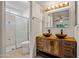 Bathroom featuring a double sink vanity, bright lighting, and a tiled walk-in shower at 16412 N 33Rd Ave, Phoenix, AZ 85053