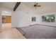 Spacious living area features vaulted ceilings, exposed beam, large windows, and neutral carpet with easy access to adjacent rooms at 16412 N 33Rd Ave, Phoenix, AZ 85053