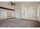 Cozy living space showcasing an exposed beam, neutral carpet, and multiple entryways, complemented by natural light and ceiling fans at 16412 N 33Rd Ave, Phoenix, AZ 85053