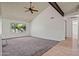 Open living room featuring vaulted ceiling, a ceiling fan, and neutral carpet, with large windows offering natural light at 16412 N 33Rd Ave, Phoenix, AZ 85053