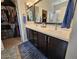 Bathroom featuring a double vanity with dark cabinets and a walk-in closet for ample storage space at 16781 S 181St Ln, Goodyear, AZ 85338