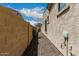 Narrow side yard with low-maintenance gravel, a retaining wall, and a glimpse of foliage at 1813 N Trowbridge --, Mesa, AZ 85207