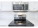 Close-up of a modern microwave, stove, and stovetop with white cabinets and countertops at 1825 W Ray Rd # 2074, Chandler, AZ 85224