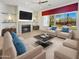 Bright living room with fireplace, ceiling fan, stylish furniture, and large windows showcasing desert landscaping at 30224 N 52Nd Pl, Cave Creek, AZ 85331