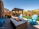 Outdoor fire pit and seating area with a covered grill station in the backyard at 30876 N 128Th Dr, Peoria, AZ 85383