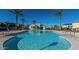 Gorgeous community pool with palm trees, lounge chairs, and a building with a bathroom at 30876 N 128Th Dr, Peoria, AZ 85383