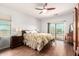 Bedroom with a floral comforter, ceiling fan, hardwood floors, and a sliding glass door to the outside at 40853 W Bravo Dr, Maricopa, AZ 85138