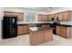 Traditional-style kitchen with wood cabinets, granite countertops, black appliances, and a center island at 4368 E Cullumber St, Gilbert, AZ 85234