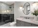 Modern bathroom with black and white tile, sleek lighting, an oval mirror, and a glass-enclosed shower at 4536 E Foothill Dr, Paradise Valley, AZ 85253