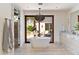 Bright bathroom features a modern soaking tub, a decorative light fixture, and glass doors to an outdoor space at 4536 E Foothill Dr, Paradise Valley, AZ 85253
