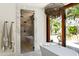 Stunning bathroom with a soaking tub, modern shower, travertine floors, and views of the outdoor landscaping at 4536 E Foothill Dr, Paradise Valley, AZ 85253