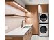 Well-lit laundry room with wooden cabinets, floating shelves, white countertop, and stacked washer/dryer units at 4536 E Foothill Dr, Paradise Valley, AZ 85253