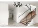 Open staircase features wood treads, black metal railings, and contemporary chandelier. Abundant natural light fills the space at 4536 E Foothill Dr, Paradise Valley, AZ 85253