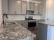 A well-appointed kitchen featuring gray cabinets, stainless steel appliances, and speckled granite countertops at 47748 W Moeller Rd, Maricopa, AZ 85139