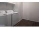 A laundry room features a white washer and dryer set on dark wood-look tile flooring at 47748 W Moeller Rd, Maricopa, AZ 85139