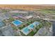Stunning aerial view of the community clubhouse with pools, tennis courts and parking at 5233 N 207Th Dr, Buckeye, AZ 85396