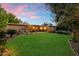 Charming backyard featuring a lush lawn, covered patio with outdoor seating, and mature trees in a serene setting at 5334 E Everett Dr, Scottsdale, AZ 85254