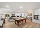 Spacious living room with a pool table, white brick fireplace, and light hardwood floors at 5334 E Everett Dr, Scottsdale, AZ 85254